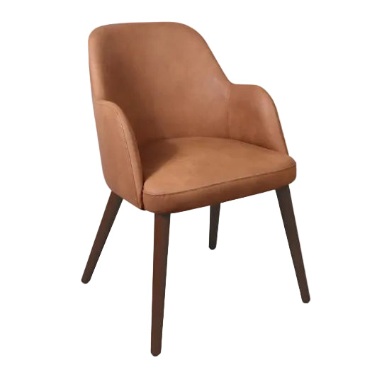 Aztec Arm Chair in Steel Grey featuring high-quality faux leather upholstery, reinforced beech wood construction with metal bracing, comfortable armrests, and commercial-grade durability for hotels, restaurants, cafés, bars, reception areas, workspaces, and care environments. Aztec Arm Chair - Cognac features smooth, cognac-colored upholstery with a curved backrest and armrests, supported by angled dark wooden legs ideal for commercial and hospitality interiors.