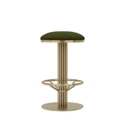 Rafferty Bar Swivel Stool upholstered in olive green velvet with a brass-finished stainless steel frame, featuring decorative vertical ridges, a circular footrest, and swivel functionality, designed for luxury hospitality, hotel, restaurant, and bar interiors. Bar stool with green cushioned seat and brass base on a beige background