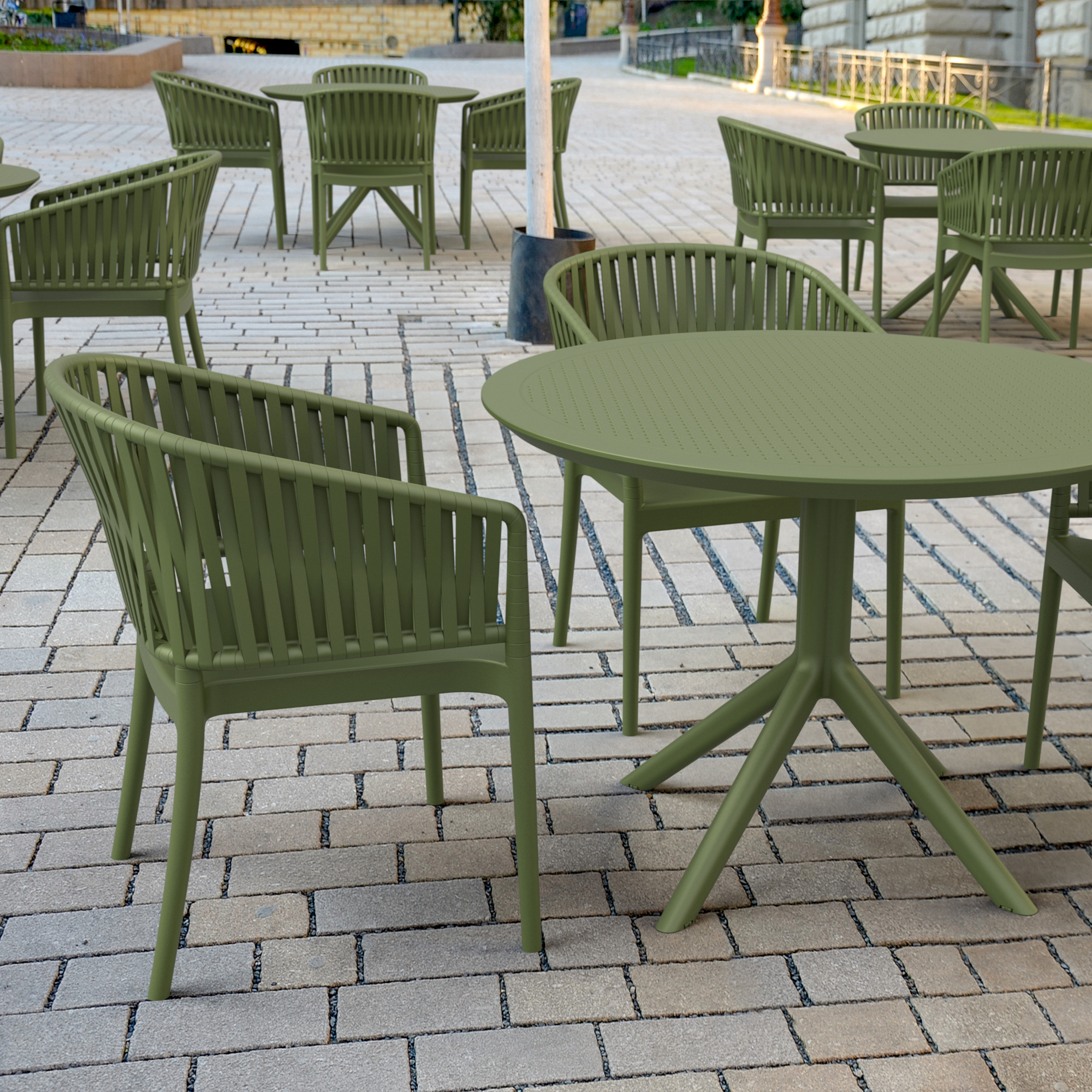 Green outdoor furniture set on a paved patio. Portofino Stacking Armchair featuring a patented 3D rope-effect backrest and armrests, glass fibre reinforced polypropylene construction, UV-resistant finish, and stackable design for hotels, restaurants, cafés, bars, rooftop terraces, and outdoor hospitality environments.