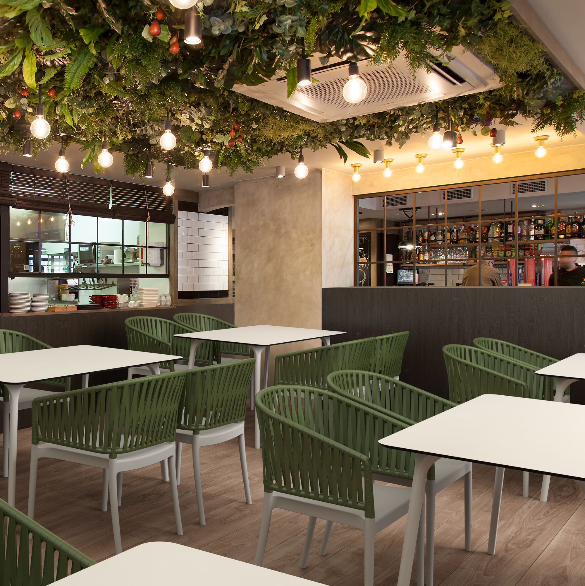 Modern restaurant interior with green chairs and white tables, decorated with hanging plants. Portofino Stacking Armchair featuring a patented 3D rope-effect backrest and armrests, glass fibre reinforced polypropylene construction, UV-resistant finish, and stackable design for hotels, restaurants, cafés, bars, rooftop terraces, and outdoor hospitality environments.