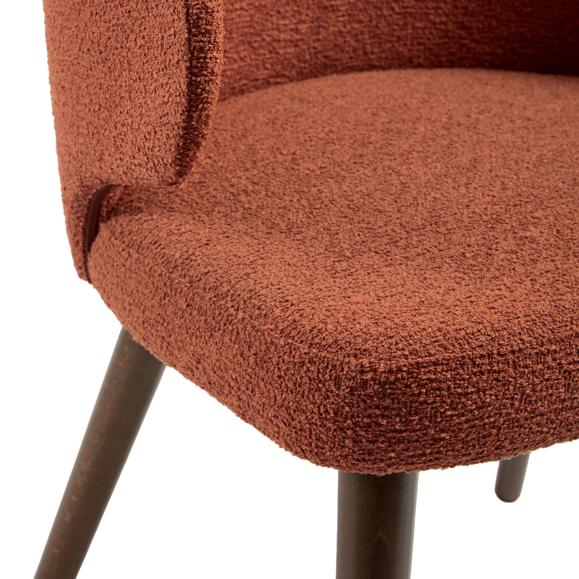 Close-up of the textured terracotta fabric upholstery and dark wooden legs of the Selma Armchair - Terracotta, highlighting its soft, durable finish and elegant craftsmanship.