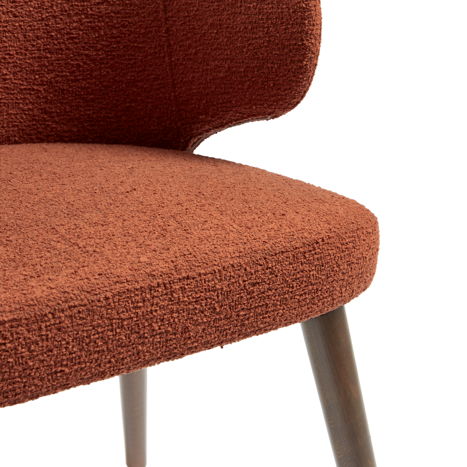 Close-up view of the textured terracotta upholstery and dark wooden legs of the Selma Armchair - Terracotta, showcasing its modern, durable design.