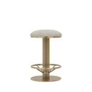 Rafferty Bar Swivel Stool upholstered in olive green velvet with a brass-finished stainless steel frame, featuring decorative vertical ridges, a circular footrest, and swivel functionality, designed for luxury hospitality, hotel, restaurant, and bar interiors. Modern stool with a textured seat and metallic frame on a beige background